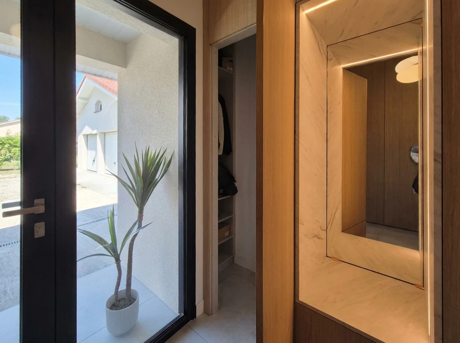 Entrée moderne d'une maison, avec porte d'entrée aluminium noire vitrée donnant sur l'extérieur