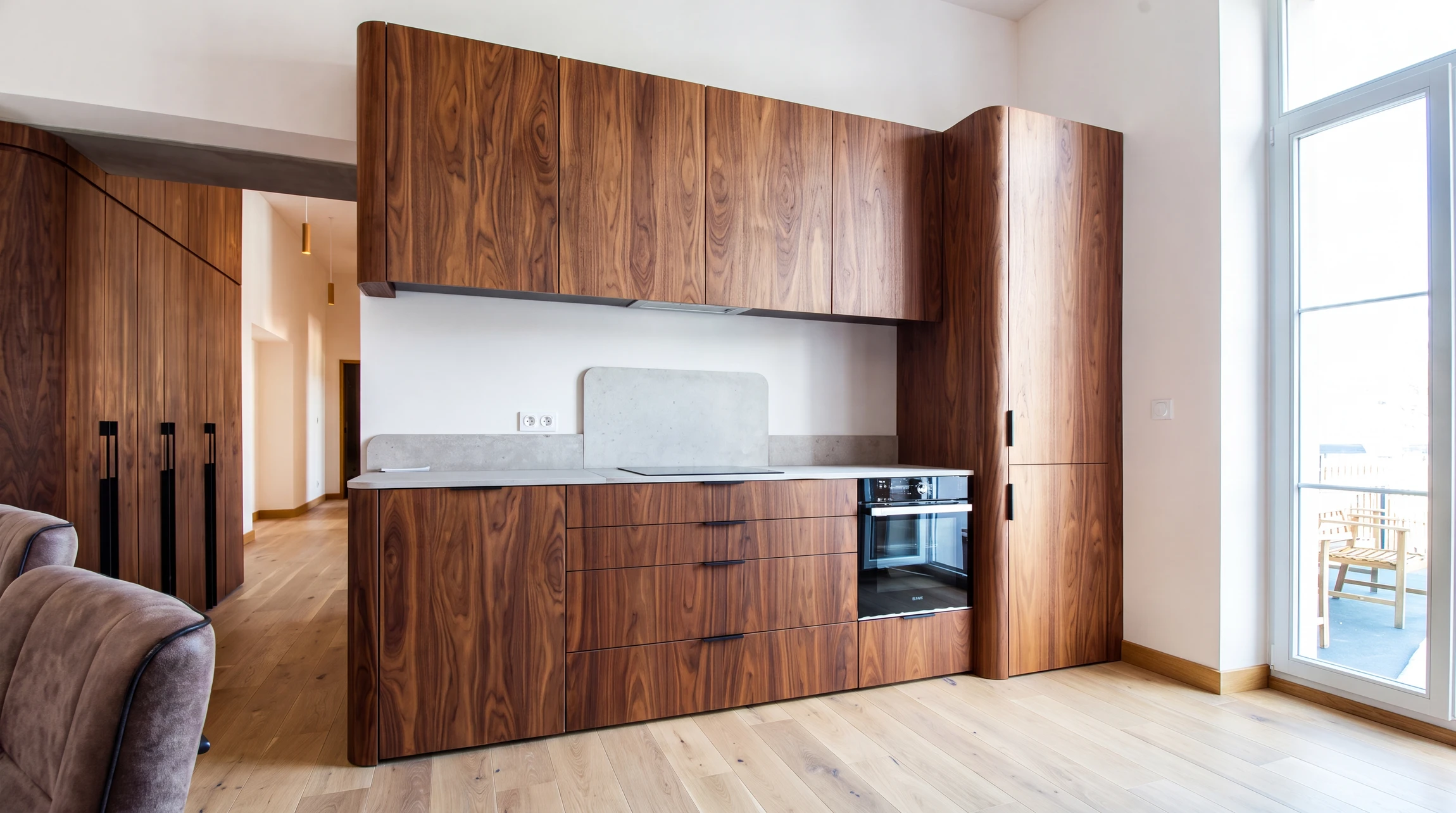 Cuisine moderne ouverte avec îlot central, plan de travail en quartz blanc, façades laquées grises, crédence miroir
