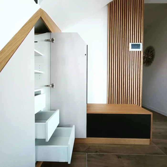 Cuisine minimaliste blanche avec une colonne d'appareils encastrés intégrant deux fours Whirlpool inox côte à côte, tiroirs et placards à poignées noires linéaires